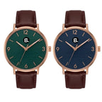 Two minimalist wristwatches with rose gold cases, leather straps, and green and blue dials.