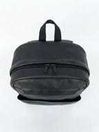 Black faux leather mini backpack with dual zipper compartments and top carry handle.